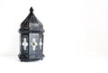 Ornamental dark Moroccan, Arabic lantern on the white table. Greeting card for Muslim community holy month Ramadan