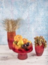 Ornamental pumpkin, fruit and grapes in a vase. Colored Glass vase fruit holder. Red glass decanter with its lid removed Royalty Free Stock Photo