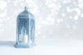 Ornamental silver and blue Arabic lantern on the table with glittering bokeh lights. Greeting card for Muslim community