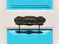 Ornamental wrought iron door handle on a white-blue door. Royalty Free Stock Photo