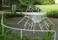 Ornamented white iron park chairs leant at table