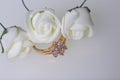 Ornaments for celebrations. Gold ring with stones and bouquet of artificial flowers. Roses beige on a white background.