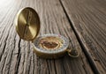 An ornate brass compass rests on a rustic wooden surface. Its lid is open, revealing a decorative Royalty Free Stock Photo