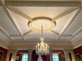 Ornate chandelier hanging from stylish stucco decorated ceiling at Stourhead House, Wiltshire