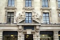 Ornate facade with man and woman statues and lion heads sculptures.