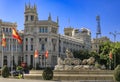 Ornate gothic Cibeles Palace or Palacio de Comunicaciones building and Cibeles fountain with Spanish flags Madrid, Spain