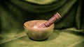 Ornate, hand-crafted Tibetan singing bowl stands against vibrant green cloth
