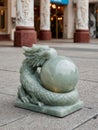Ornate jade dragon sculpture holding a sphere in urban setting. Royalty Free Stock Photo