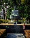 Ornate Japanese Buddhist Buddha statue shrine with greenery in urban Tokyo Japan.