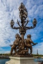 Ornate lamp with cupids on the Alexander III Bridge with the Eiffel Tower in the background in Paris