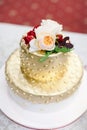 Ornate luxury golden polka dot festive wedding cake with flowers pink and red roses on top stands on white table