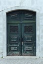 Ornate old ancient green wooden door of stone building decorated with forgings carvings ornaments with peeling paint. Royalty Free Stock Photo