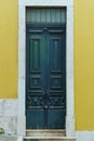 Ornate old high green wooden door of yellow stone building house with white frame decorated with forgings carvings. Royalty Free Stock Photo