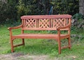 Ornate park bench on the grass in front of some lush woodland Royalty Free Stock Photo