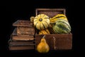 Ornate pumpkin in a old wooden crate and a book. Vegetables and old publications on the dark table