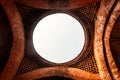 An ornate roof of a ceiling with a circular opening with a view of the sky in the ruins of the ancient Adina Masjid mosque in the