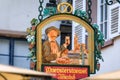 Ornate sign with a pretzel and a man at an Alsatian winstub, Strasbourg, France