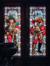Ornate stained glass window picturing two heroic knights in red clothes