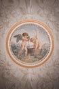 Ornate Venetian-style ceiling painting of cherubs bathing in a tub in luxurious room