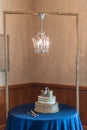 Ornate wedding cake illuminated by a small, elegant chandelier, creating a stunning atmosphere