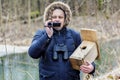 Ornithologist with camcorder and bird cage near river