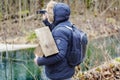 Ornithologist with camcorder and bird cage in the park near river