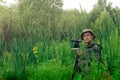 Ornithologist with a spotting scope and notepad among the tall grass in the valley Royalty Free Stock Photo