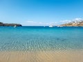 Ornos empty sandy beach, calm sea moored yachts background. Mykonos island, Cyclades Greece
