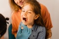 Oropharyngoscopy procedure for child. Otolaryngologist examines child throat with spatula. Family consultation with