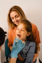 Oropharyngoscopy procedure for child. Otolaryngologist examines child throat with spatula. Family consultation with