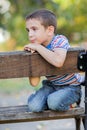 Orphan, unhappy boy sitting on a park bench and crying Royalty Free Stock Photo