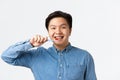Orthodontics, dental care and hygiene concept. Close-up of friendly-looking smiling asian man brushing teeth with braces Royalty Free Stock Photo