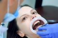 Orthodontist is fixing metal part on woman's patient teeth before condylography. Royalty Free Stock Photo
