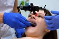 Orthodontist installs dental facebow on woman face, process of prosthetics.