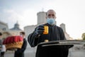 An orthodox christian priest with a surgical mask due to the covid-19 pandemic shares the Holy Light during the orthodox Easter Royalty Free Stock Photo