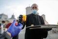 An orthodox christian priest with a surgical mask due to the covid-19 pandemic shares the Holy Light during the orthodox Easter Royalty Free Stock Photo