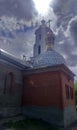 Orthodox Church on the background of the cloudy sky and the sun shining from the cloud gap on the cross