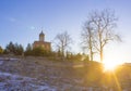 Orthodox church on a hill near the forest. Winter sunset landscape with clear blue sky and sun rays Royalty Free Stock Photo