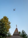 Orthodox cross and plane. Orthodox wooden church and a passenger plane flying into the sky