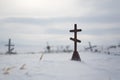 Orthodox cross on a snow-covered grave in the cemetery of an abandoned Arctic village Royalty Free Stock Photo