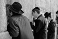 Orthodox hassidic religious jews dressed in black traditional outfit pray at the wailing wall