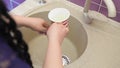 An Orthodox Jewish woman washes her hands from a mug, alternately pouring netilat yadaim on each hand