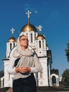 Orthodox lifestyle woman in a scarf stands on the background of the Orthodox Church.