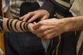 An orthodox man, wearing prayer shawl, put a Jewish Tefillin on A young man arm preparing for a pray, as part of a Jewish ritual