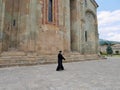 Orthodox priest walking past Svetitskhoveli Cathedral, Mtskheta, Georgia.