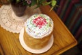 Orthodox Russian Eastern European Easter bread Kulich is lying on a table in a white plate near a vase of flowers