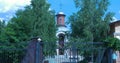 Orthodox temple orange brick with sunny ray, flowering green trees in foreground. Blue sky white clouds. Pray, holy