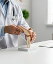 Orthopedic doctor explaining knee anatomy with joint model, demonstrating structure awareness, mobility function, injury Royalty Free Stock Photo