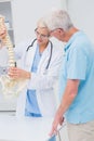 Orthopedic doctor and senior patient discussing over anatomical spine Royalty Free Stock Photo