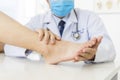 The orthopedic doctor or surgeon in white gown examined the patient with foot pain problem.